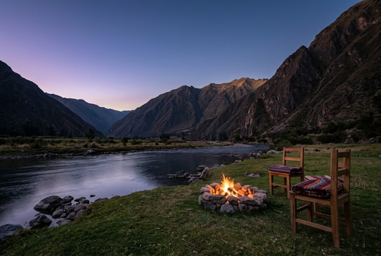 A small fire burning at dusk in the Sacred Valley, with mountains behind.
